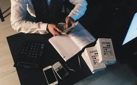 Agent ubezpieczeniowy liczy pieniądze, obok leżą telefony i notatnik. Zastanawiasz się, ile zarabia agent ubezpieczeniowy?