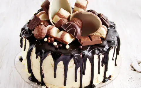 Wyjątkowy tort kinder bueno, oblany czekoladą, ozdobiony pralinkami i kawałkami batoników.
