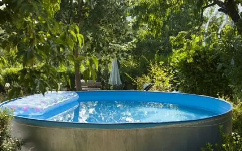 Installation piscine hors sol terminée, prête pour les baignades estivales. Un matelas gonflable flotte sur l'eau bleue.
