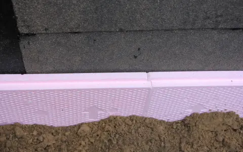 Różowa folia kubełkowa na styropianie chroni fundament przed wilgocią i uszkodzeniami.