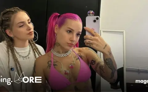 Dwie dziewczyny, jedna z różowymi włosami, druga z warkoczami, pozują do selfie. Jedna z nich, w różowym bikini, ma widoczne tatuaże. W tle logo "Going. MORE".