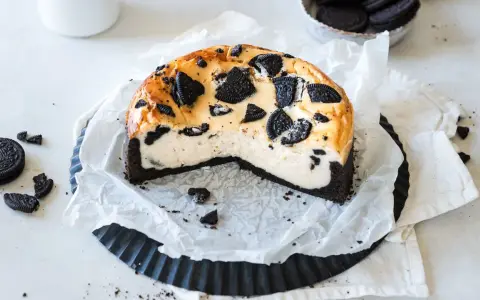 Ein cremiger Oreo Kuchen mit einem dunklen Keksboden, dekoriert mit ganzen und zerbrochenen Oreos.
