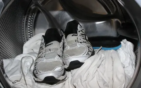 Scarpe da ginnastica pronte per essere lavate in lavatrice, insieme ad alcuni asciugamani bianchi.