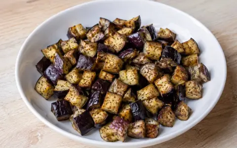 Melanzane a cubetti, cotte in friggitrice ad aria, dorate e saporite, pronte per essere gustate.