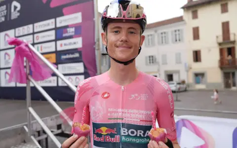 Radfahrer des Teams Red Bull Bora Hansgrohe hält einen Muffin mit Kerze.