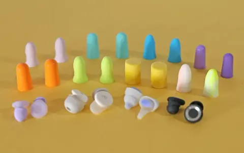 Apprenez comment mettre des bouchons d'oreilles en mousse. Divers bouchons colorés et écouteurs sans fil sont disposés sur fond jaune.