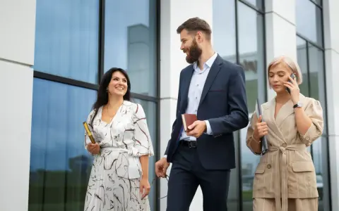 Mujeres con estilo para una conferencia: una con vestido estampado y clutch dorado, otra con traje de lino a rayas y hablando por teléfono.