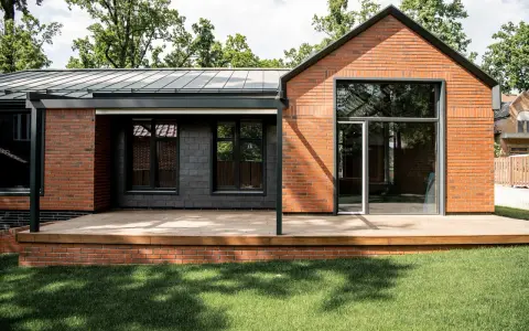 Nowoczesny dom z cegły i ciemnej elewacji, z drewnianym tarasem. Marzysz o takim? Dowiedz się, jak uzyskać pozwolenie na budowę.