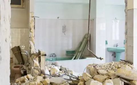 Ruiny łazienki po remoncie. Zniszczone ściany, gruz i wanna. Kara za mieszkanie w nieodebranym domu.