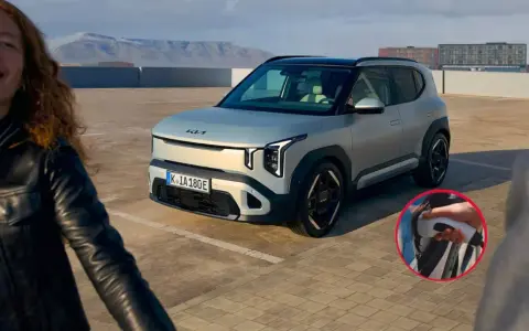Un hombre sonriente se acerca a su primer vehículo eléctrico, un moderno SUV plateado, listo para cargarlo.