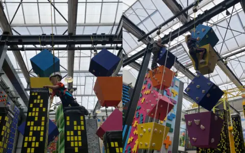 Kinder klettern auf bunte Würfel und Wolkenkratzer in einer Kletterhalle, die an einen Magic Mountain Berlin erinnert.