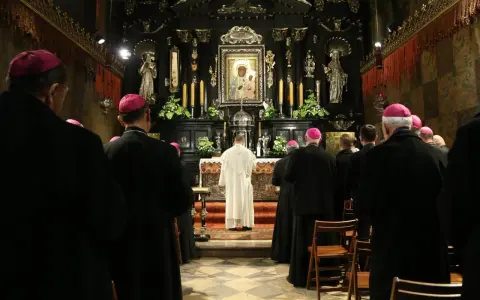 Uroczyste msze święte na Jasnej Górze. Biskupi w czarnych szatach i różowych biretach modlą się przed ołtarzem z cudownym obrazem Matki Bożej.