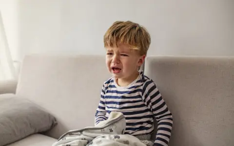 Mały chłopiec płacze na kanapie, przykryty kocykiem. Czyżby to był regres snu, kiedy?