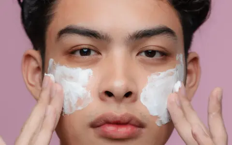 Uomo applica crema sul viso per una pelle perfetta.