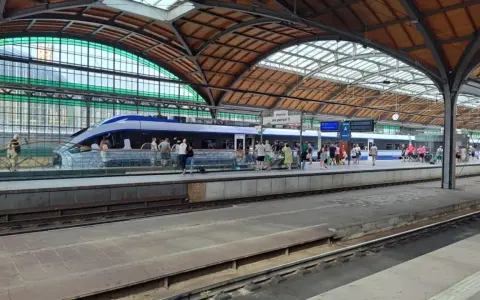 Nowoczesny pociąg kraków wrocław na peronie, pasażerowie czekają na podróż pod zabytkowym zadaszeniem dworca.