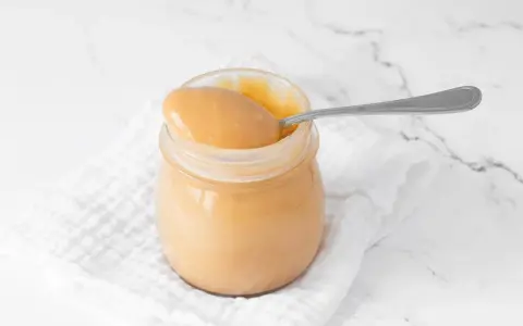 Un tarro de manjar blanco cremoso, listo para ser disfrutado con una cuchara.
