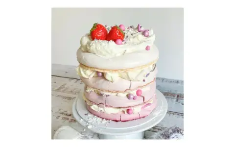 Eine mehrstöckige Baiser Torte mit Sahne, Erdbeeren und rosa Zuckerperlen.