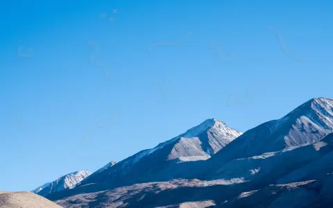 Sullo sfondo di montagne innevate, un cielo azzurro limpido è punteggiato da forme sinchisi scintillante, come piccoli puntini e curve sinuose.