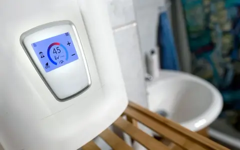 Moderner durchlauferhitzer 18 oder 21 kW zeigt 45°C an. Im Hintergrund ein Waschbecken.