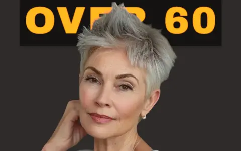 Donna con un elegante corto taglio capelli over 60, sguardo intenso e un sorriso accennato.