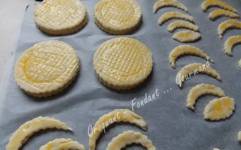 Sur une plaque, des disques de pâte feuilletée prêts à cuire, certains en forme de croissant, pour une délicieuse croute vol au vent.