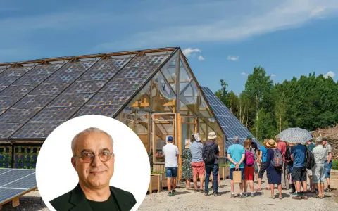 En grupp besökare tittar på ett växthus med solpaneler på taket, en del av auterra solar-projektet.