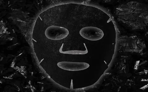 Maschera al carbone, con i suoi benefici, appare come un volto misterioso incorniciato da texture scure e profonde.