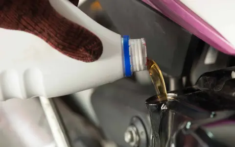 Rękawica nalewa nowy olej do silnika motocykla podczas wymiany oleju.