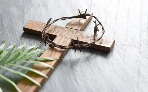 Holzkreuz mit Dornenkrone und Palmblatt. Christen fasten Regeln, um sich auf Ostern vorzubereiten.