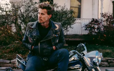 Austin North, protagonista di film e programmi TV, con giacca di pelle e moto.
