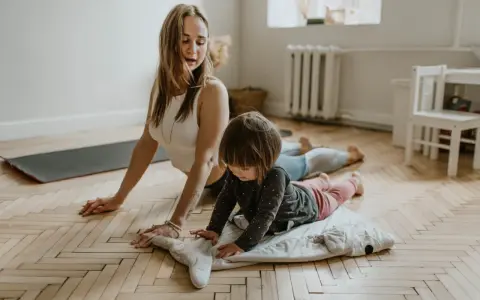 Mama i dziecko ćwiczą jogę. Maluch leży na poduszce w kształcie wieloryba, a mama w pozycji kobry. To świetne ćwiczenia relaksacyjne dla dzieci.