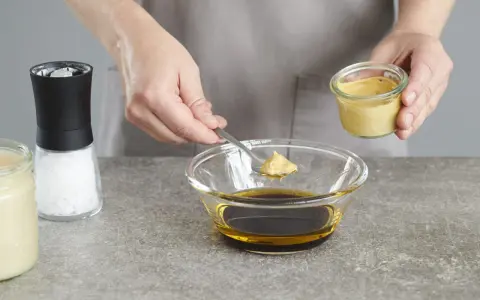 Senf wird zu einer Schüssel mit Öl und Balsamico-Dressing gegeben.