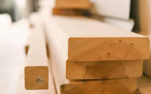 Stapel von unbehandelten Holzbrettern, bereit für den Bau eines Dach-Ringbalkens.