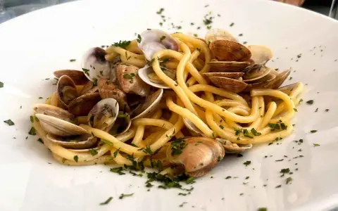 Spaghetti con lupini di mare freschi, un piatto che profuma di mare e tradizione, guarnito con prezzemolo tritato.