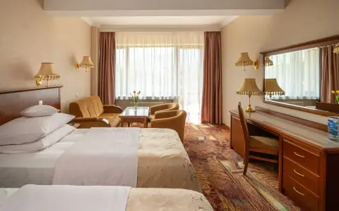 Pokój w hotelu Gołębiowski Wisła: dwa łóżka, kanapa, fotele, biurko i lustro.