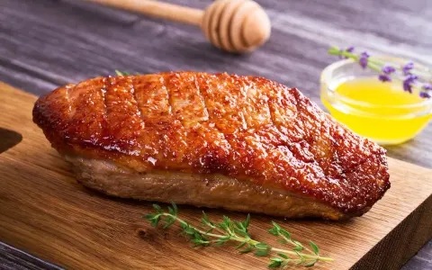Un magret de canard au barbecue, la peau dorée et croustillante, prêt à être dégusté avec une touche de miel et de thym.