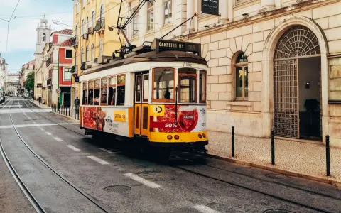 Gelbes Tram fährt durch Lissabon. Perfekt für eine Erkundungstour beim Lissabon wandern.