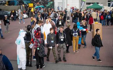 Tłum ludzi w kostiumach, w tym jednorożec i tygrys, na wydarzeniu Pyrkon. Co to za festiwal?