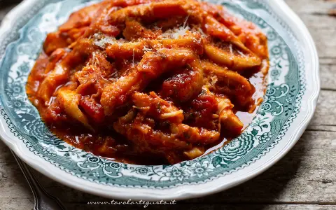 Un piatto fumante di trippa alla romana, ricca e saporita, servita su un piatto decorato.