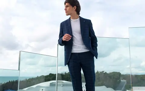 Uomo con tailleur blu a quadri, maglione bianco. Perfetto per capire con che scarpe abbinare.