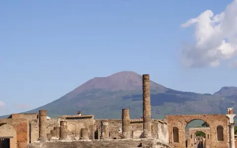 Rovine di Pompei con il Vesuvio sullo sfondo. Un'idea per cosa visitare a Pompei in un giorno, tra colonne antiche e storia millenaria.