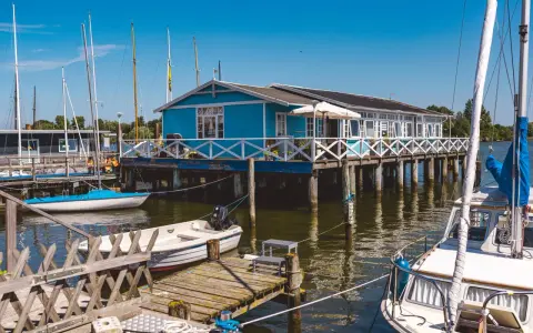 Blaues Haus am Wasser mit Booten, ein idyllisches Motiv für Schlei Ausflugsziele.