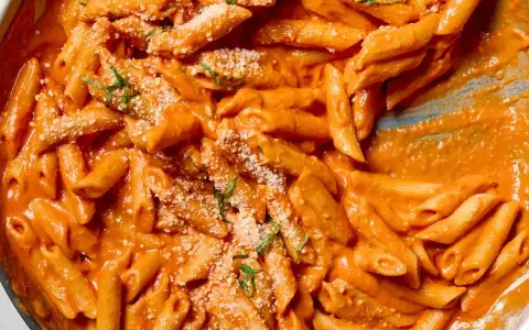 Penne alla vodka w kremowym sosie pomidorowym, posypane parmezanem i bazylią.