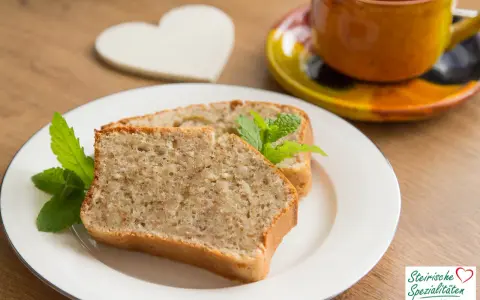 Zwei Scheiben saftiger Becherkuchen mit Joghurt, garniert mit Minze, neben einer Tasse Kaffee.