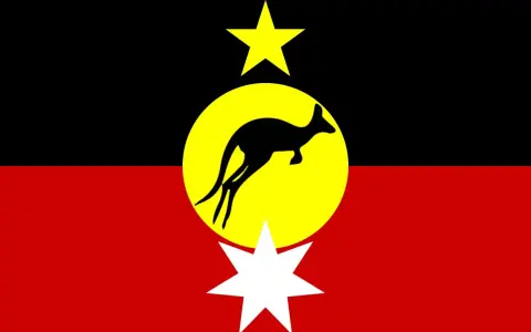Flaga Australii rdzennej: czarny pas, żółte koło z czarnym kangurem, żółta gwiazda i biała gwiazda.