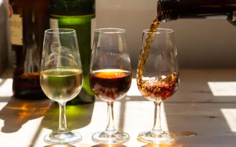 Drei Gläser mit Sherry, die die Vielfalt der sherry Herkunft zeigen. Ein helles, ein dunkles und ein drittes, das gerade eingeschenkt wird.