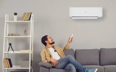 Uomo sorride usando telecomando per accendere un cool condizionatore. Il suo significato è comfort e benessere in casa.