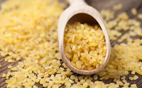Kasza bulgur na drewnianej łyżce. Niska kasza bulgur indeks glikemiczny sprawia, że jest idealna dla diabetyków.
