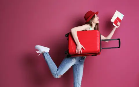 Kobieta z walizką i paszportem zastanawia się, ile kosztuje dodatkowy bagaż w Ryanair.