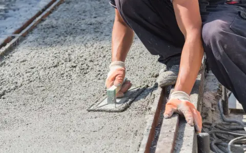 Robotnik wygładza świeży beton, dbając o właściwe proporcje dla betonu B10.